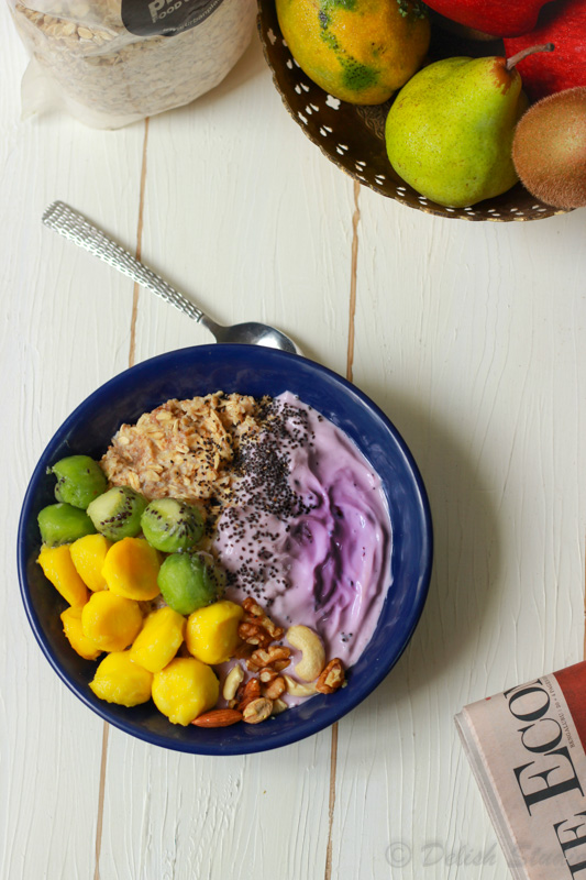 Top view of mango and kiwi scoops with easy overnight oats with blueberry yoghurt in a blue bowl