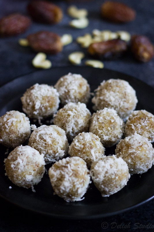 plate full of refined sugar free coconut date balls with coconut and dates at the back