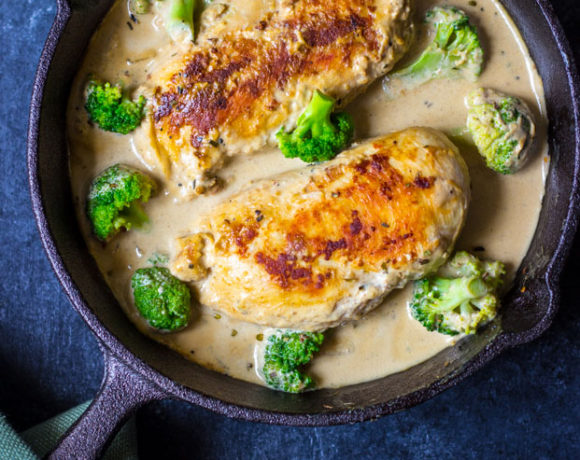 Creamy garlic chicken with broccoli in a skillet on a blue background