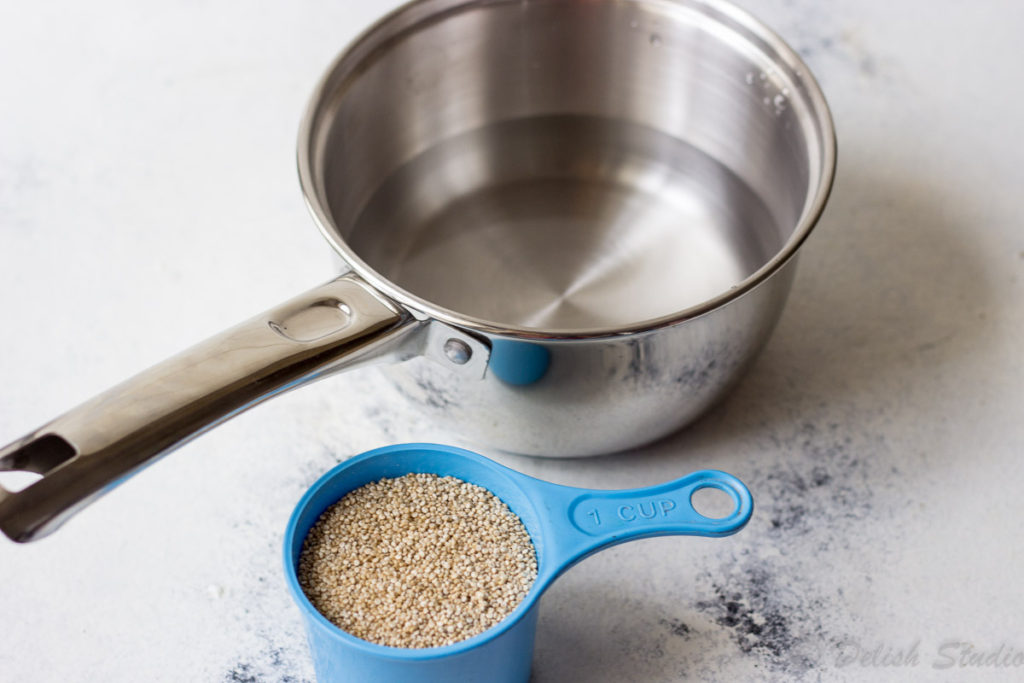 Saucepan with water and quinoa seeds to cook quinoa for making quinoa patties.