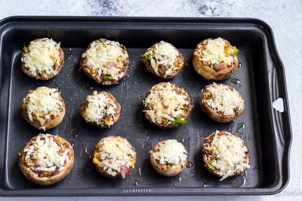 Party appetiser Cheese stuffed mushrooms lined in a baking tin ready to go into oven to get baked