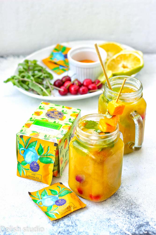 Aam Salaam mango iced tea mocktail in two mason jars with fresh fruits and mangoes